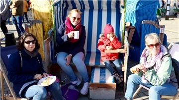 Vier Personen essen Kuchen und trinken Kaffee