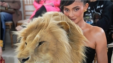 Kylie Jenner hinter einem täuschend echt aussehenden Löwenkopf.