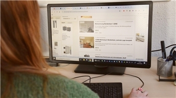 Eine Frau schaut auf einen Bildschirm. Sie ist auf Wohnungssuche in Nordenham.