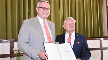 Landrat Marco Prietz (links) überreichte Erich Gajdzik die von Bundespräsident Frank-Walter Steinmeier unterzeichnete Urkunde und steckte ihm den Verdienstorden an. 