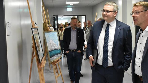 Kooperation zweier Schulen: Jetzt hat der Zevener Bildungsweg neue Räume Zwei Männer in Anzügen stehen rechts im Bild, links stehen Staffeleien mit Bildern.