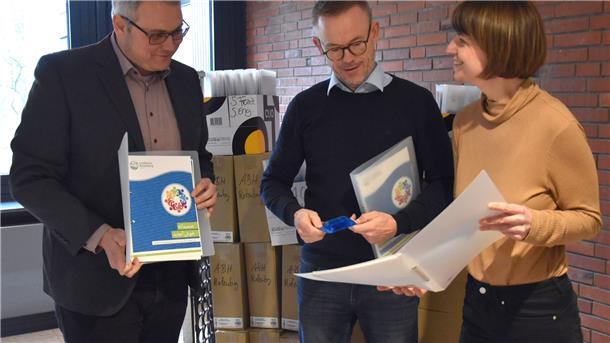 Erste Willkommensmappen übergeben Präsentierende mit den Informationsmappen