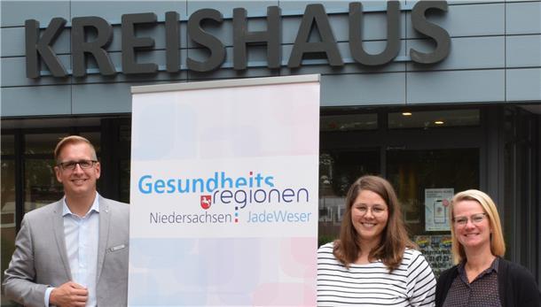 Drei Leute und ein Aufsteller vor dem Kreishaus in Brake