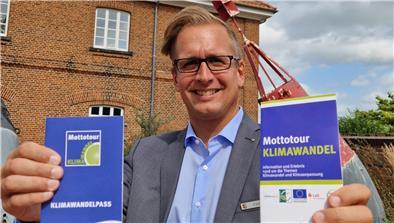 „Mottotour Klimawandel“ bietet Bewegung und Informationen in der Wesermarsch Landrat Stephan Siefken wirbt für die „Mottotour Klimawandel“. Im Hintergrund ist der Braker Telegraph zu sehen, vor dem eine der neun Stationen zu finden ist.