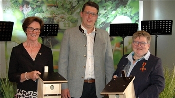 Ein Mann und zwei Frauen gucken in die Kamera.