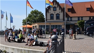 Gäste sitzen am Fähranleger. Sie wollen zur Sail nach Bremerhaven. 