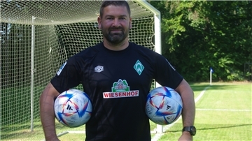 Lars Neugebauer steht mit zwei Bällen unter dem Arm vor einem Tor.