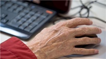 Ein älterer Mann sitzt an einem Computer.