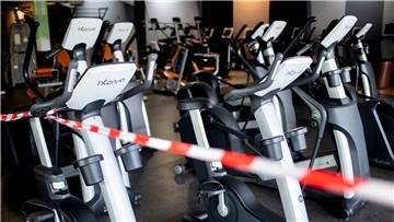 Ein rot-weißes Flatterband ist an Fahrradtrainern befestigt, die in einem Fitnessstudio stehen.