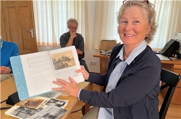 Frau zeigt Mappe mit Aufzeichnungen.