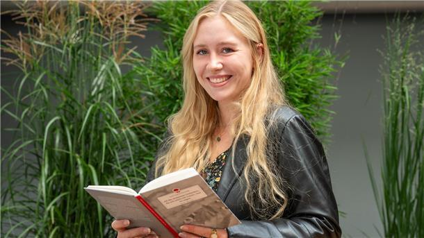 Eine junge Frau hält ein Buch in den Händen.
