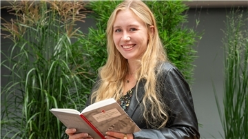 Eine junge Frau hält ein Buch in den Händen.