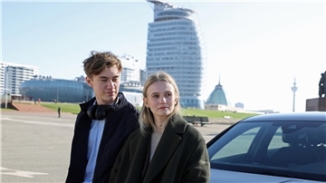 Ein junger Mann und eine junge Frau stehen in Bremerhaven vor dem Hotel Sail City.