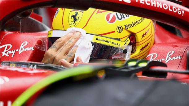 Lewis Hamilton wischt sich den Regen vom Visier.