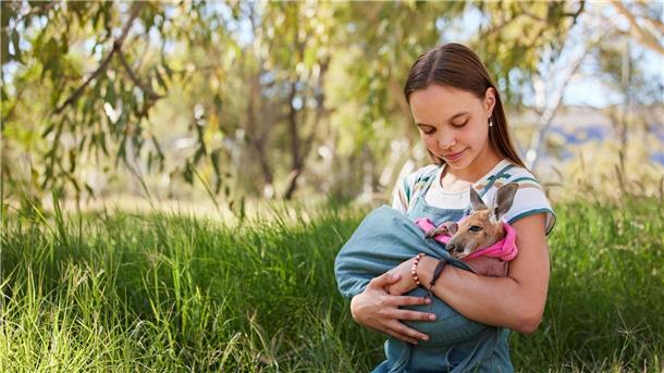 Lilly hält ein gerettetes junges Känguru in ihren Armen.