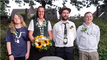 Vier Personen stehen vor einer Hecke.