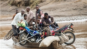 Männer transportieren in Malawi ihre geretteten Habseligkeiten mit einem Holzboot.