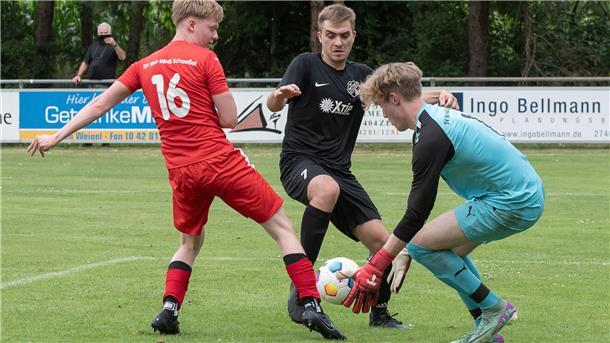 Oldendorf wirft im Elfmeterschießen Kreisligist Scheeßel raus Drei Männer, einer in einem schwarzen Trikot, einer in einem roten Trikot und einer in einem grünen Trikot, versuchen einen Fußball zu kriegen.