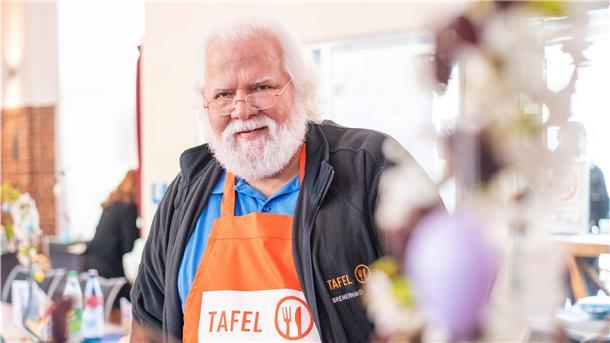 Manfred Jabs steht hinter dem Tresen der Essensausgabe und blickt in Richtung Kamera.
