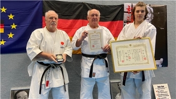 Manfred Schäfer (Mitte) freut sich über seine Ehren-Urkunde. Karate-Bundesprüfer Bernhard Keller (links) präsentiert die Ehren-Medaille. Konstantin Keller (rechts), amtierender „Deutscher Karate Meister“, zeigt Schäfers Diplom vor.