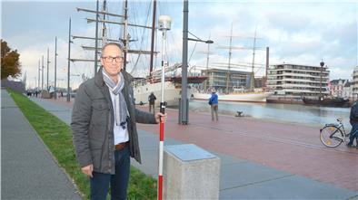 Marc Kewes steht mit einem Vermessungsstab am GPS-Referenzpunkt, den das Vermessungs- und Katasteramt am Neuen Hafen in Bremerhaven eingerichtet hat.
