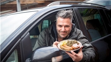 Marco Tienz, Grünkohltaxi-Betreiber, sitzt mit einem Grünkohlteller in seinem Auto.