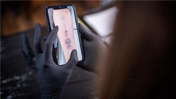 Auf dem Display eines Handys ist ein Tattoo Motiv zu sehen. 
