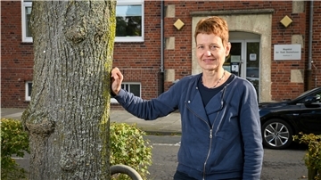 Martina Völger lehnt mit einer Hand an einem Baum.