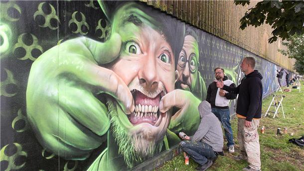 Mathias Blanck alias Ast (Mitte), Andreas Buschhardt alias Thoe (rechts) und Enrico Mau alias Demut (links unten) vor ihrem Werk „Keep Smiling“ in der Oststraße.