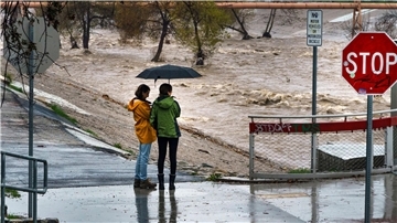 Menschen beobachten die großen Mengen an Regenwasser im Los Angeles River.