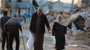Menschen gehen an zerstörten Gebäuden im Flüchtlingslager Al-Maghazi im Zentrum des Gazastreifens vorbei. Das Bangen um eine Feuerpause vor Ramadan geht weiter.