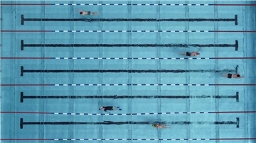 Menschen schwimmen in einem Freibad.