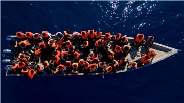 Menschen sitzen in einem Holzboot im Mittelmeer. Symbolbild