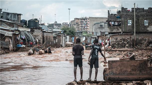 Menschen stehen am Ufer eines überfluteten Flusses in den Mathare-Slums in Nairobi.