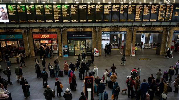 Menschen stehen an Anzeigetafeln im Bahnhof Kings Cross in London. Streiks behindern den Reiseverkehr zu Weihnachten erheblich.