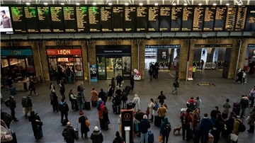 Menschen stehen an Anzeigetafeln im Bahnhof Kings Cross in London. Streiks behindern den Reiseverkehr zu Weihnachten erheblich.