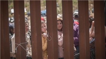 Menschen stehen hinter der Grenzmauer zwischen Mexiko und USA und hoffen darauf, in die USA einreisen zu können.