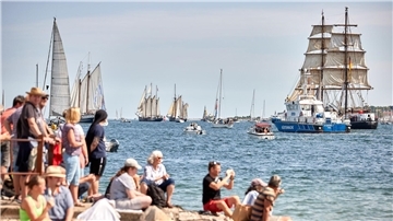 Menschen verfolgen an der Förde die Windjammerparade.