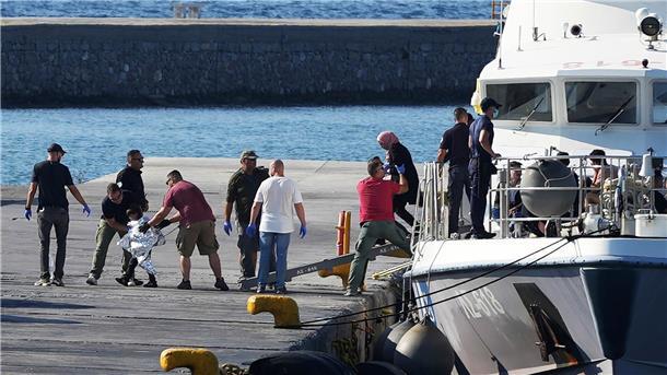 Menschen werden nach der Rettungsaktion im Hafen von Mytilini auf Lesbos von Beamten der Küstenwache eskortiert.