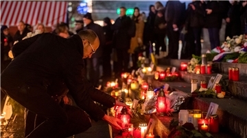 Menschen zünden bei der Gedenkveranstaltung zum Terroranschlag auf dem Berliner Breitscheidplatz an der Gedächtniskirche Kerzen an.
