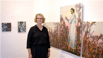 Eine Frau steht vor einem dreiteiligen Bild in einer Galerie. 
