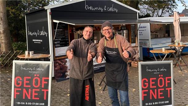 Zwei Männer stehen vor ihren Foodtrucks.
