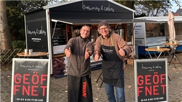 Zwei Männer stehen vor ihren Foodtrucks.
