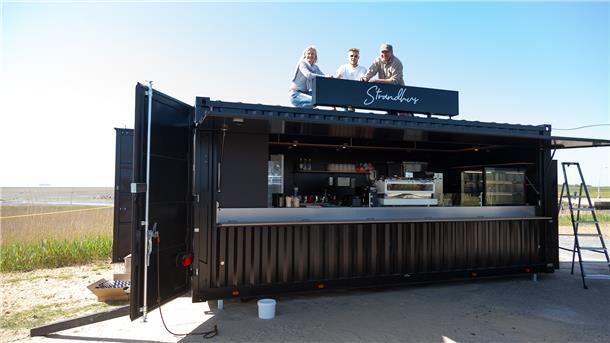 Ein „Strandhus“ mit eigenem Sandstrand Michaela, Leonard und John Reinhardt testen den Sitz der gerade installierten „Strandhus“-Aufschrift auf dem Dach des Cafébar-Containers am Strand von Wremen.
