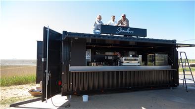 Michaela, Leonard und John Reinhardt testen den Sitz der gerade installierten „Strandhus“-Aufschrift auf dem Dach des Cafébar-Containers am Strand von Wremen.