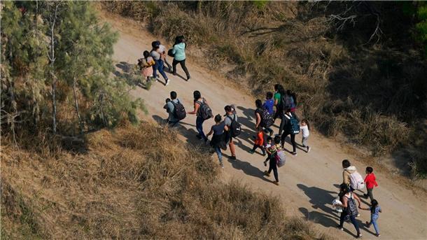 Migranten gehen im Süden von Texas über einen Feldweg, nachdem sie die Grenze zwischen den USA und Mexiko überquert haben.