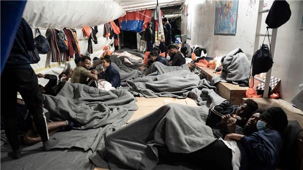 Migranten sind in Decken eingewickelt, während sie sich auf dem Deck des Rettungsschiffs Ocean Viking im Mittelmeer nahe der Küste Siziliens in Süditalien versammeln.