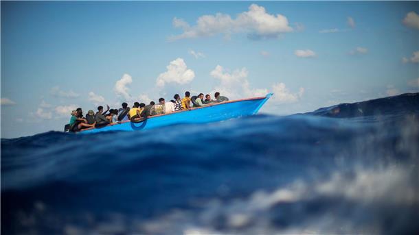 Mehr als 600 Neuankömmlinge auf Lampedusa - Kind vermisst Migranten sitzen in einem Holzboot im Mittelmeer nahe der Insel Lampedusa: Die kleine Insel gehört seit Jahren zu den Brennpunkten illegaler Migration (Archivfoto).