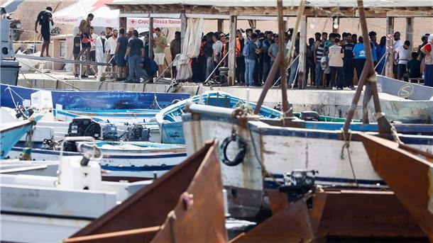 Debatte über Migrationsobergrenze - Rom beschließt Maßnahmen Migranten stehen an einem Hafen auf Lampedusa.