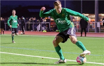 Ein Mann in grünem Trikot tritt gegen einen Ball.